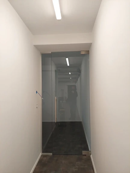 Nihajna vrata iz prozornega kaljenega stekla z mat okovom in minimalnimi profili. Pisarna, Ljubljana