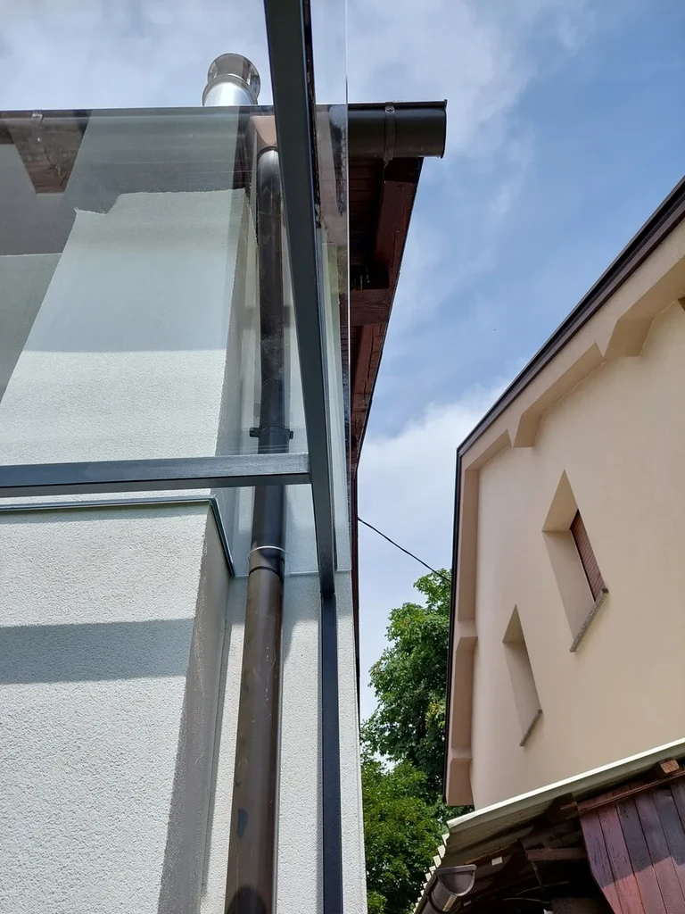 Detajl steklenega nadstreška — steklo iz enega kosa z izrezom za žleb. Prozorno kaljeno lepljeno steklo, natančna izdelava po meri. Družinska hiša, Ljubljana