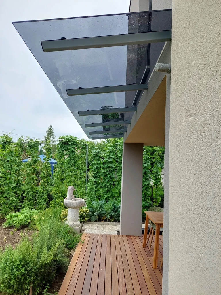 Stekleni nadstrešek iz temnega kaljenega lepljenega stekla nad prehodom na teraso. Varnostno laminirano steklo, minimalni nos